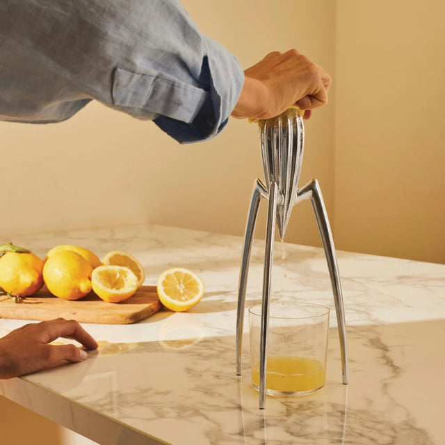 Alessi Zitruspresse Juicy Salif in Anwendung – frisch gepresster Zitronensaft läuft ins Glas