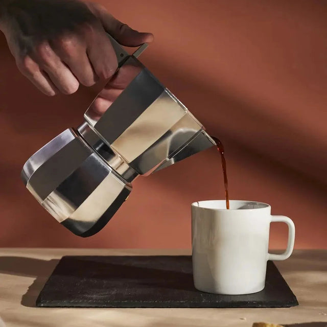 Alessi Moka Espressokocher in der Hand, Kaffee wird eingeschenkt