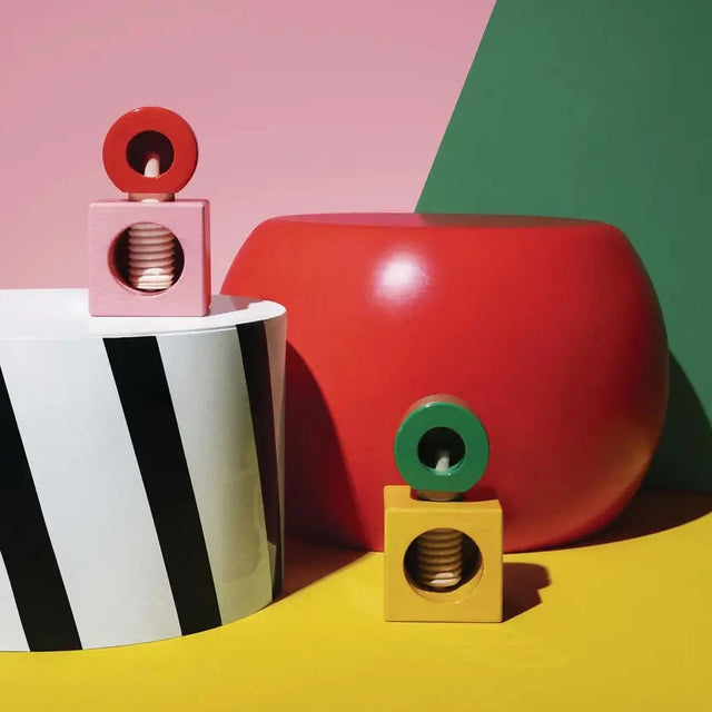 Alessi Nussknacker ES20 in beiden Varianten – Rosa-Rot und Gelb-Grün, Lifestyle-Aufnahme im Memphis-Stil
