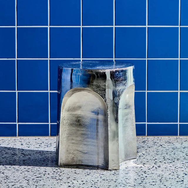 House Doctor Riga Beistelltisch Silber als Hocker vor blauer Fliesenwand