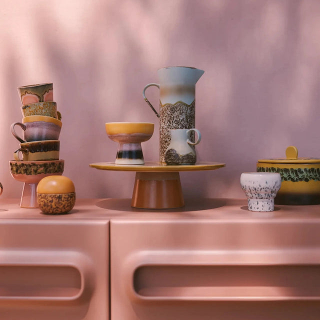 HKliving 70s Ceramics Kollektion – Jug Shell Karaffe im Stillleben mit Tassen und Schalen auf rosa Kommode