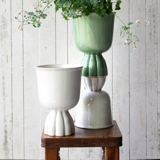 Martina Übertopf Offwhite als Blumentopf auf Holzhocker neben grünem Martina Topf, Wikholm Form