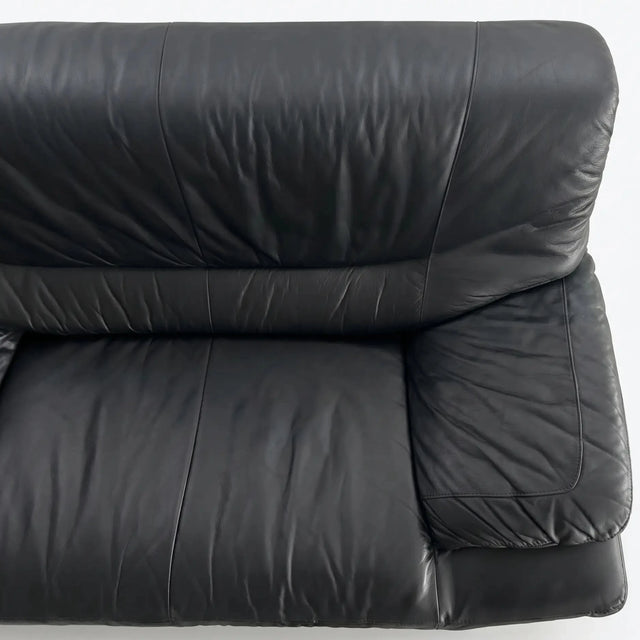 Nahaufnahme der weichen Nappaleder-Struktur und der festen Kissen-Armlehne eines postmodernen Designklassiker-Sofas vor weißem Hintergrund
