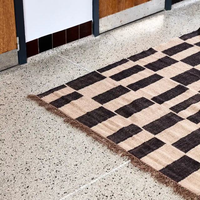 Teppich Graph in Schwarz und Natur mit asymmetrischem Muster und Fransen von House Doctor – Wohnbeispiel (180 × 180 cm)