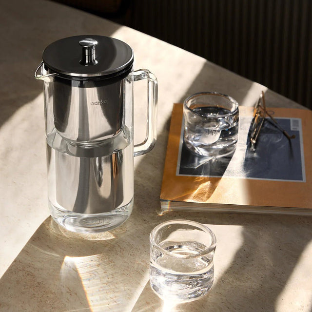 Wasserfilter Edelstahl Purifier auf einem Marmortisch mit Trinkgläsern - Aarke