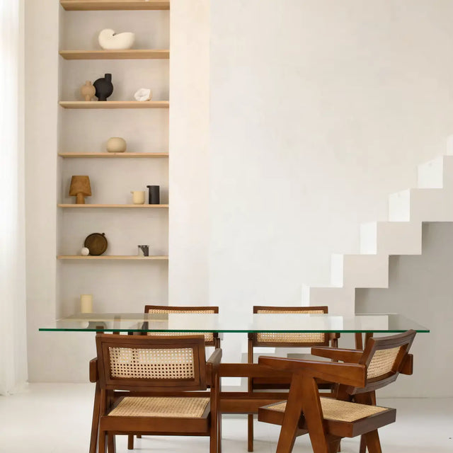 Esstisch mit Glasplatte und vier Stühlen aus Teak mit Rattangeflecht vor Wandnische mit Keramik-Objekten und weißer Treppe – Mid Century Esszimmer