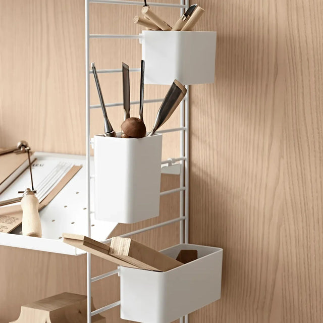 String Organizer Aufbewahrungsboxen in Weiß an einer String Wandleiter, gefüllt mit Werkzeug neben einem Regalboden