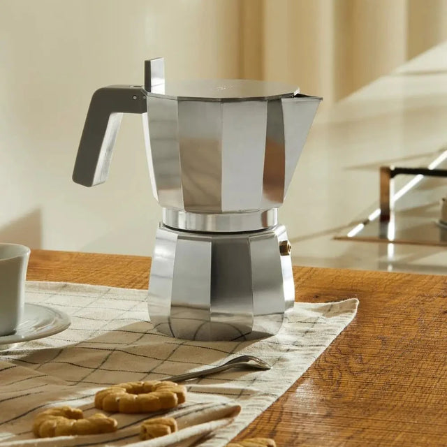 Alessi Moka Espressokocher Induktion auf einem Holztisch mit Espressotasse und Keksen – Lifestyle