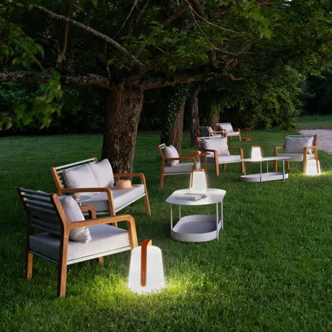 Fermob Balad² Akku-Lampe Kandierte Orange im Garten zwischen Loungemöbeln - Fermob