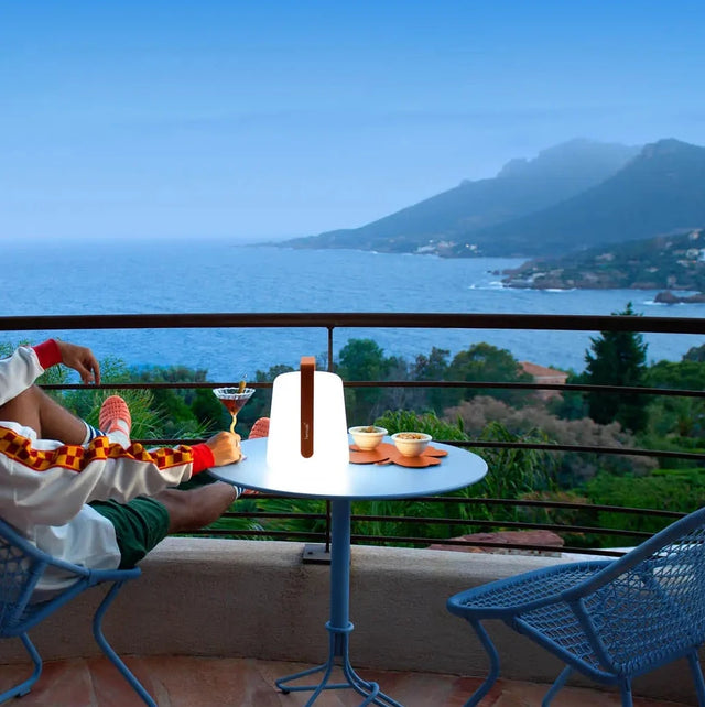 Fermob Balad² Akku-Lampe Kandierte Orange auf Terrassentisch mit Meerblick - Fermob