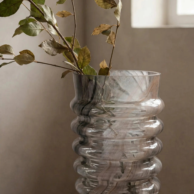 ISAA Vase Fiprion lichtbraun mit grünem Zweig vor beiger Wand
