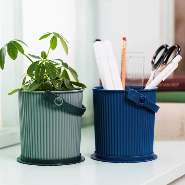 Hachiman Omnioutil Eimer Baby 0,7L als Stiftehalter und Blumentopf auf dem Schreibtisch – in Baked Green und Navy